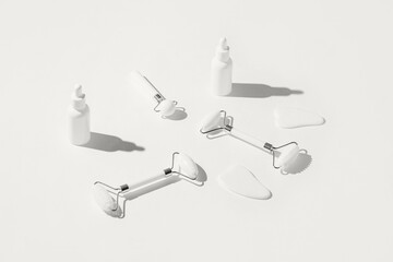 Cosmetic facial kit for home skin care and spa. Face rollers and gua sha massagers made from white jade, bottles of serum or essential. Color of the year 2026 inspired background