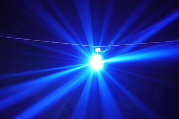 Blue spotlight burst with radiant beams in dark night sky