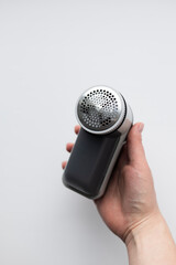 Fabric shaver in female hand on white background close-up.
