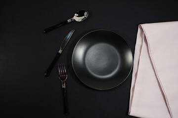Elegant dining arrangement with modern silverware on sleek black background, perfect for upscale restaurants, fine dining promotions and sophisticated culinary blogs