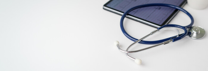 A stethoscope is on a table next to a tablet