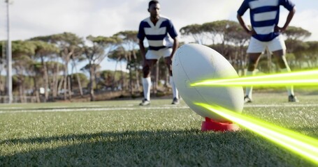 Balancing white rugby ball on red tee on grass pitch, neon streaks, players wearing striped jerseys