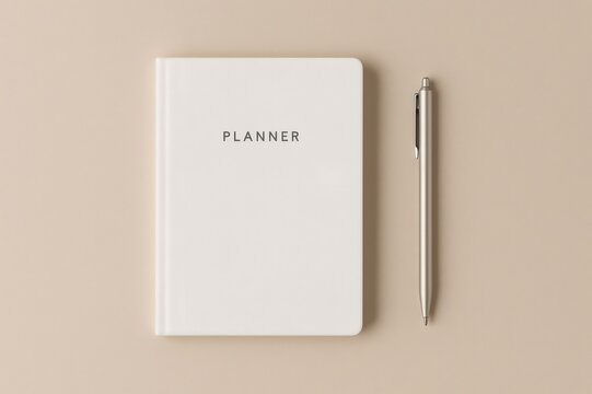 Simple planner and pen displaying productivity, planning, and scheduling tools on a neutral beige background in a flat lay