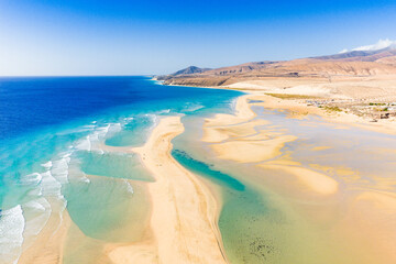 Fototapeta premium Playa de Sotavento is a famous beach on the southeastern coast of Fuerteventura, known for its long stretches of golden sand, turquoise water, and consistent winds