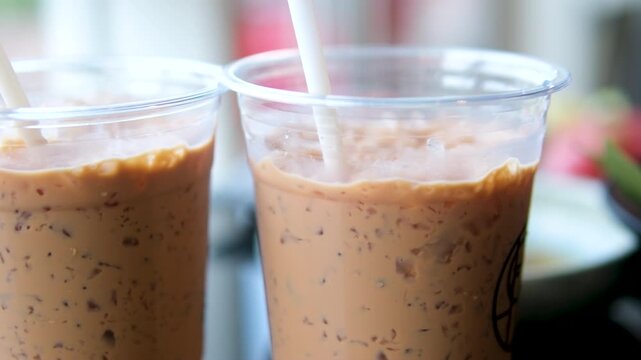 two plastic cups Iced coffee table cappuccino in glass. Milkshake with coffee in beautiful cup. Coffee drink with foam. process of making latte. close-up of female hand .