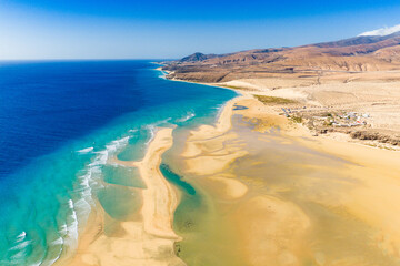 Playa de Sotavento is a famous beach on the southeastern coast of Fuerteventura, known for its long stretches of golden sand, turquoise water, and consistent winds