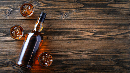 Whiskey Bottle with Glasses and Ice on Rustic Wooden Background, Copy Space