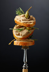 Sandwiches with liver pate garnished with rosemary and capers.