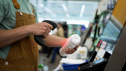 Buyer scanning various items at a self-checkout kiosk in a modern hardware store, utilizing a handheld barcode scanner for efficient and contactless payment