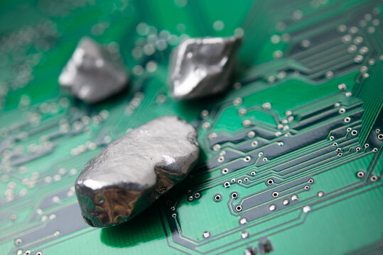 Mineral rare earth element on green electronic circuit board background copy space. US vs China chip war, tech war, semiconductor industry concept. China curbs on exports of rare earth element to US.