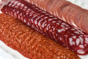 Slices of different sausages. Slices of tasty ham and salami sausage in vacuum packpage. Food background.