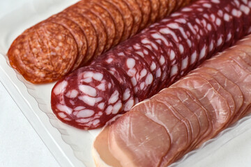 Slices of different sausages, top view. Slised meat, tasty ham and salami sausage in vacuum package.Set of different sausage.