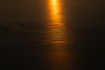 Tekstura lodu z naturalnymi wzorami rozświetlona ciepłym światłem zachodzącego słońca. Złota poświata podkreśla delikatne pęknięcia i struktury, tworząc abstrakcyjną i nastrojową zimową scenerię.