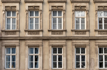 Obraz premium Classic facade of an old European building with symmetrical windows, decorative moldings and architectural details