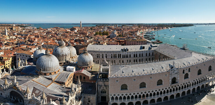 Aerial view of the Doge's Palace and St Mark's Basilica, where the domed roofs meet the intricate stonework, against the backdrop of the vast Adriatic sea, Venice, Veneto, Italy.