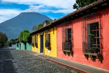 Typical colorful houses on a street in the historic Old town of Antigua Guatemala with Fuego volcano in background, Guatemala