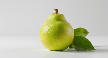 A single green pear with leaves sits on a white surface, simple and fresh