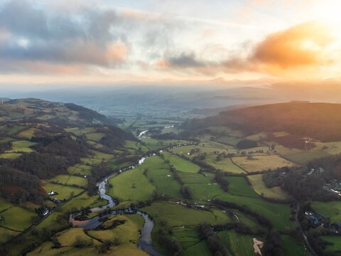 Aerial view of the River Dee snaking through the lush green valleys, with the sunlight kissing the hills, Bala, Wales, United Kingdom.