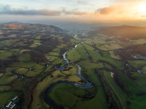 Aerial view of the meandering River Dee s snaking through the lush green valley, contrasting with the rugged hills in the distance, Bala, Wales, United Kingdom.