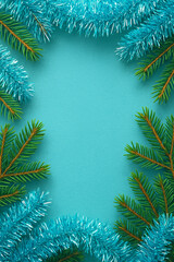 Christmas turquoise background with fir branches and tinsel, copy space