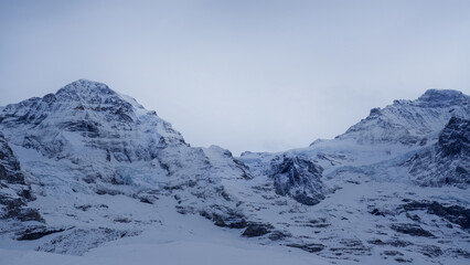 Snow-covered alpine peaks captured from the Kleine Scheidegg area in Switzerland, showcasing dramatic rocky slopes and a serene winter atmosphere