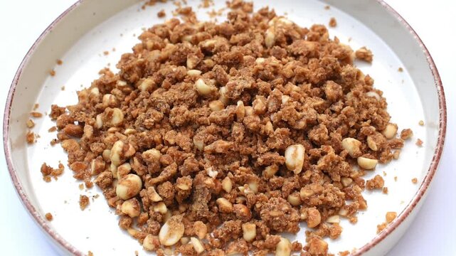 Granulated jaggery in a plate, til gur moongfali flavor jaggery made with sesame seeds, peanuts and raw sugarcane jaggery.