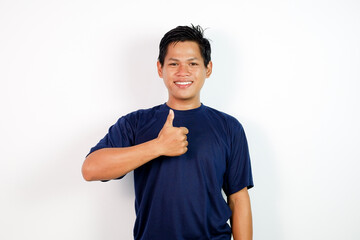 A smiling young Asian man in a navy blue shirt stands against a clean white background, giving a thumbs up.