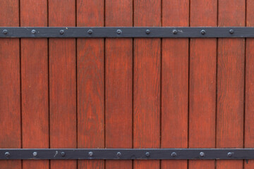 Czerwone drewniane drzwi z czarnymi metalowymi okuciami i nitami w stylu rustykalnym, widok z bliska © Henryk Guziak