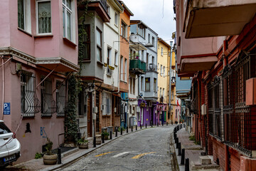 A curved, narrow cobblestone street lined with colorful historic houses featuring traditional Ottoman bay windows (cumba) in the Balat district. Istanbul, Turkey.
