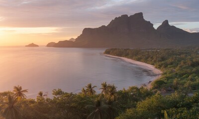 Coastal landscape shows a mountain on an island with beach and palm trees at sunset