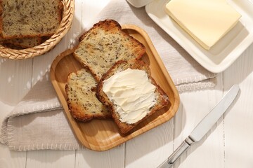 Bread slices with butter on white wooden table, flat lay