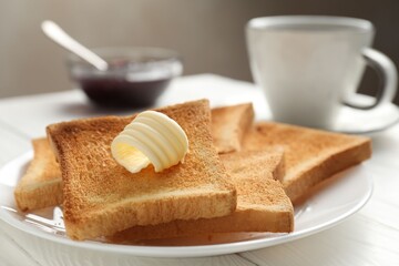 Fresh toasted bread slices served with butter and tea on white wooden table, closeup