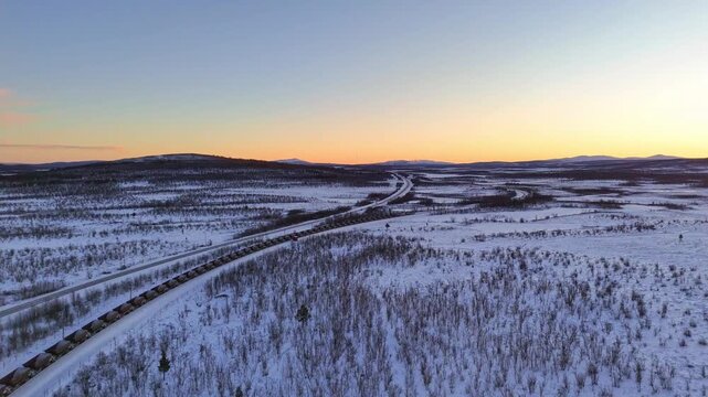 Freight train with iron ore, aerial view, Sunset over arctic mountain landscape in Lapland, Sweden, road and railroad between Kiruna and Narvik