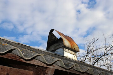 Broken chimney cap on a roof with clear sky in the background during daytime