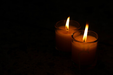 A candle burned on a glass holder in the dark, a symbol of hope.	