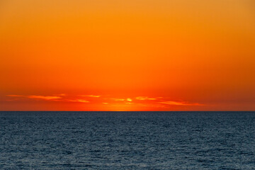 Soft fading light after sunset creating a warm red-orange sky above the sea, Portugal, Ovar –...