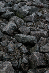 Uneven cluster of rocks suspended on jagged mountain slope with plants