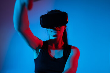 Woman engaged in virtual reality experience wearing VR headset in vivid blue red neon futuristic lighting