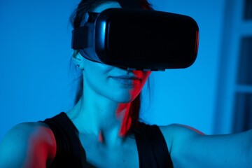 Young woman using virtual reality headset in immersive blue and red futuristic technology setting