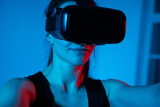 Young woman using virtual reality headset in immersive blue and red futuristic technology setting