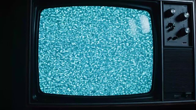 CRT Television Turquoise Static - An old CRT television screen displays turquoise static and noise. The vintage television set is in a dark area, the screen bright with static.