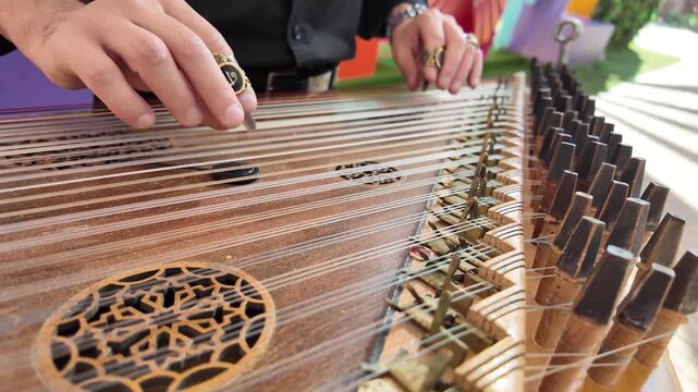 old man playing qanun, traditional turkish instrument, kanun, turkish man performing wooden string at celebration of The United Arab Emirates Independence Day ( 54th uae national day ) in Al Ain Zoo