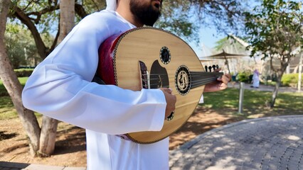 A person playing an oud, a prominent stringed instrument in Middle Eastern music at celebration of The United Arab Emirates Independence Day ( 54th uae national day ) in Al Ain Zoo	