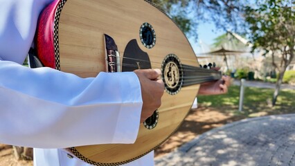 A person playing an oud, a prominent stringed instrument in Middle Eastern music at celebration of The United Arab Emirates Independence Day ( 54th uae national day ) in Al Ain Zoo	