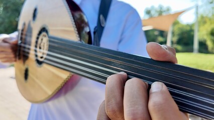 A person playing an oud, a prominent stringed instrument in Middle Eastern music at celebration of The United Arab Emirates Independence Day ( 54th uae national day ) in Al Ain Zoo	