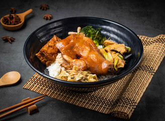 Braised chicken rice bowl with tofu and vegetables served on a bamboo mat with star anise, appetizing meal