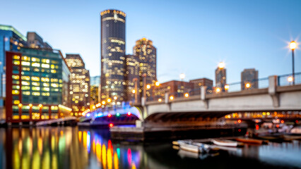 Conceptual image of Boston at Boston Harbor and Financial District at night with blurred buildings and bokeh balls.