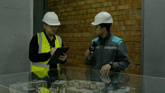 Two construction workers in yellow vests discussing plans at an outdoor site