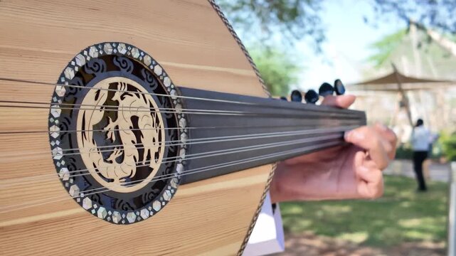 A person playing an oud, a prominent stringed instrument in Middle Eastern music at celebration of The United Arab Emirates Independence Day ( 54th uae national day ) in Al Ain Zoo	