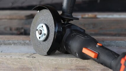 Cordless angle grinder on wooden boards. Tool for repair and construction. Cordless angle grinder close-up. Tool in the country